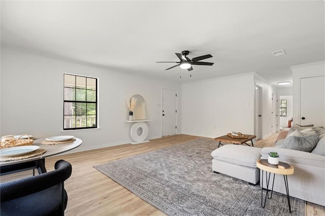 living room featuring ornamental molding, visible vents, ceiling fan, and light wood finished floors