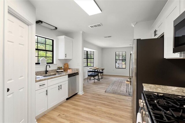 kitchen with a sink, stainless steel appliances, a healthy amount of sunlight, visible vents, and white cabinets