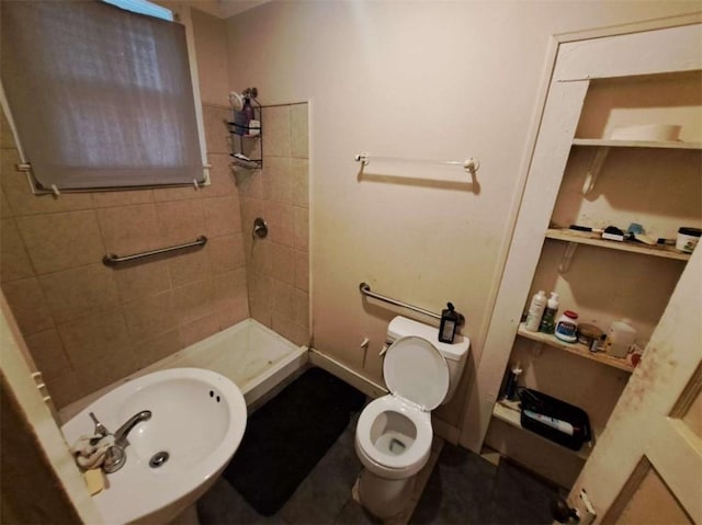 bathroom featuring sink, toilet, and tiled shower