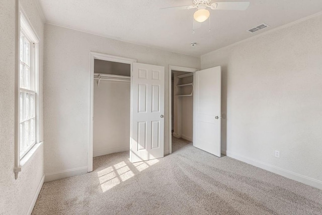 unfurnished bedroom featuring ceiling fan, light colored carpet, ornamental molding, and a closet