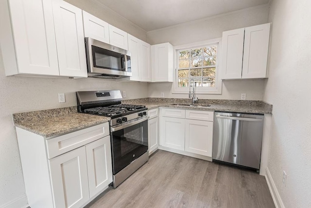 kitchen with sink, stainless steel appliances, light hardwood / wood-style floors, and white cabinets