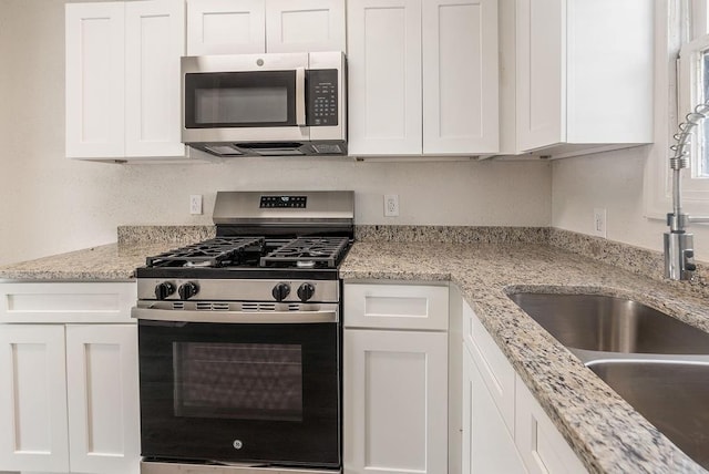 kitchen featuring stainless steel appliances, light stone countertops, and white cabinets