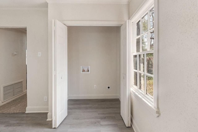 clothes washing area with electric dryer hookup, washer hookup, wood-type flooring, and ornamental molding