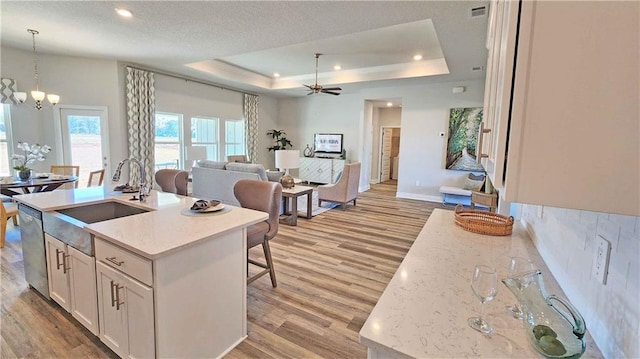 2295 Nadine Ln, Mobile, AL 36695 - kitchen with light wood-type flooring, white cabinets, open floor plan, dishwasher, and a tray ceiling