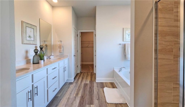 2295 Nadine Ln, Mobile, AL 36695 - bathroom featuring double vanity, a garden tub, a stall shower, wood finished floors, and a walk in closet