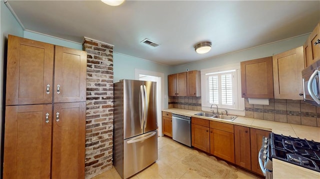 21 Crenshaw St, Mobile, AL 36606 - kitchen with appliances with stainless steel finishes, a sink, backsplash, brown cabinetry, and light tile patterned flooring