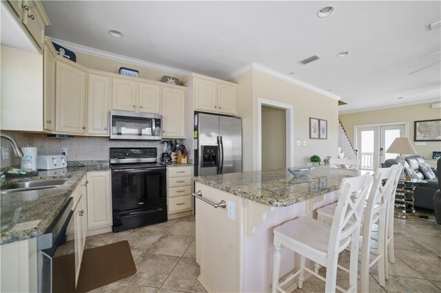 kitchen with stainless steel appliances, visible vents, decorative backsplash, a sink, and a kitchen island