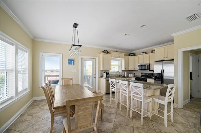 kitchen with visible vents, a center island, stainless steel appliances, crown molding, and cream cabinetry