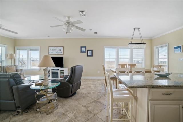 living area with ceiling fan, a wealth of natural light, visible vents, and crown molding