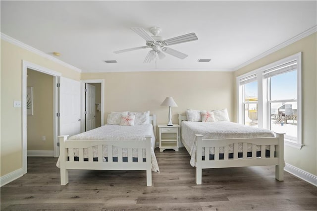 bedroom featuring ornamental molding, wood finished floors, visible vents, and baseboards