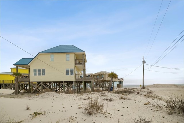 back of property featuring metal roof, a balcony, and stairs