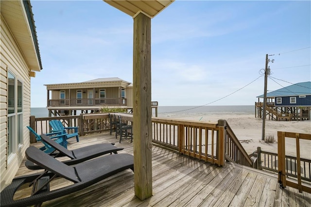 wooden deck with a water view and a beach view