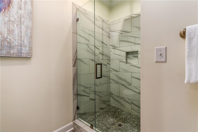 bathroom with a shower stall and baseboards