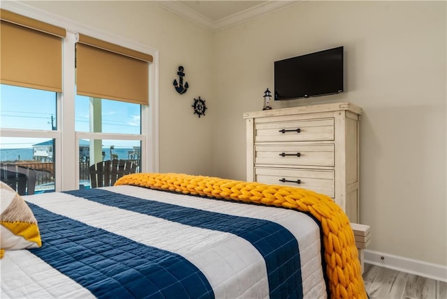 bedroom with baseboards, wood finished floors, and crown molding