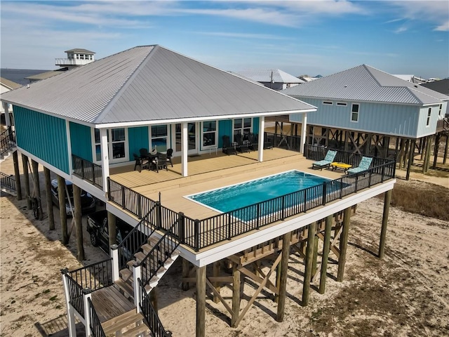 rear view of house with a patio area, a fenced in pool, metal roof, and stairs