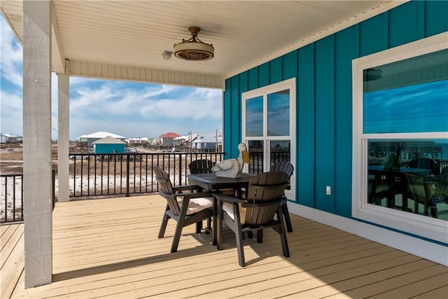 wooden terrace with outdoor dining space and ceiling fan