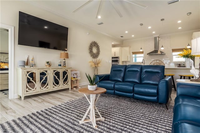 living area featuring light wood finished floors, recessed lighting, crown molding, and ceiling fan