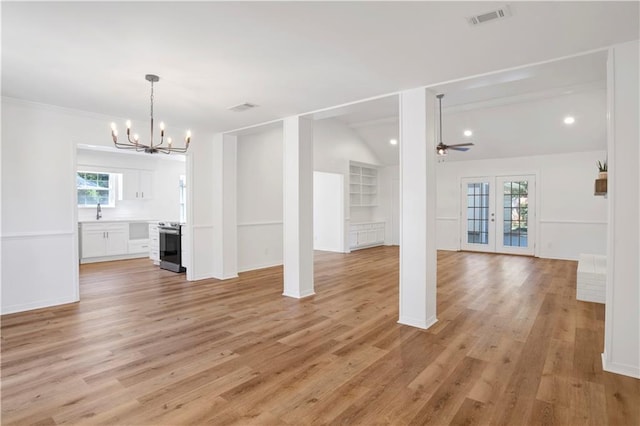 unfurnished living room featuring vaulted ceiling, ceiling fan with notable chandelier, french doors, and light wood-type flooring