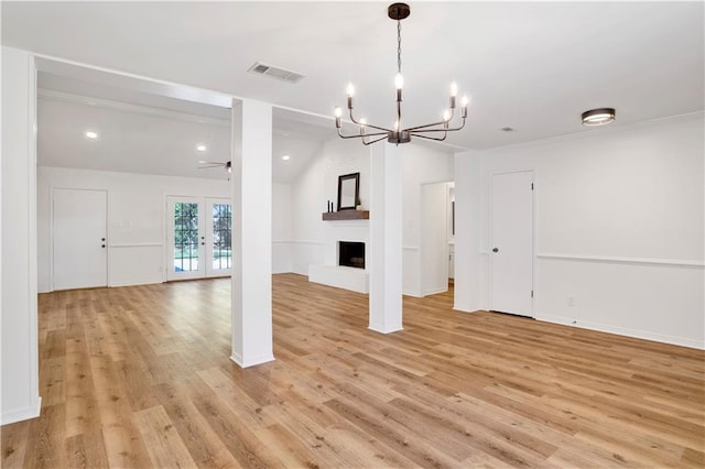 unfurnished living room featuring french doors, vaulted ceiling, light hardwood / wood-style flooring, a large fireplace, and ceiling fan