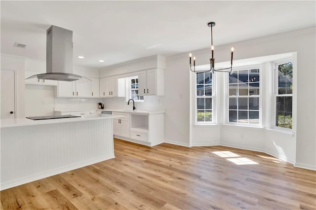 kitchen featuring white cabinetry, island range hood, hanging light fixtures, light hardwood / wood-style flooring, and black electric cooktop