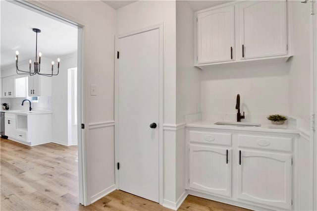 5912 Cansler Dr, Mobile, AL 36609 - kitchen with a sink, light wood-style floors, white cabinetry, and a chandelier