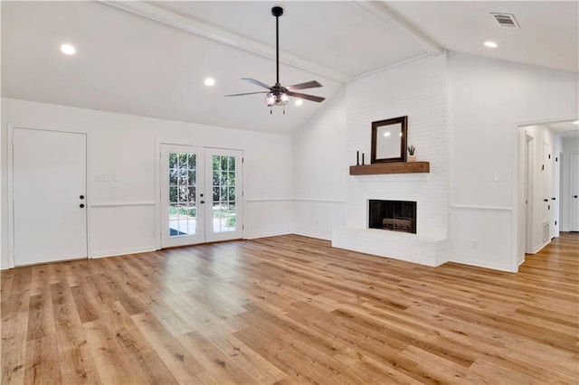 unfurnished living room with french doors, light wood-type flooring, a brick fireplace, and beamed ceiling