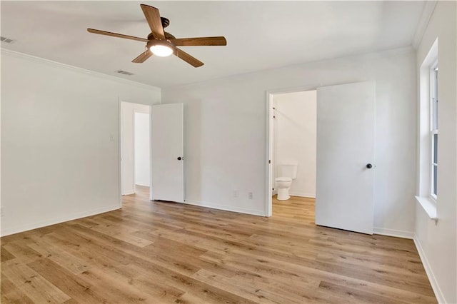 interior space featuring multiple windows, crown molding, light wood-type flooring, and ensuite bath