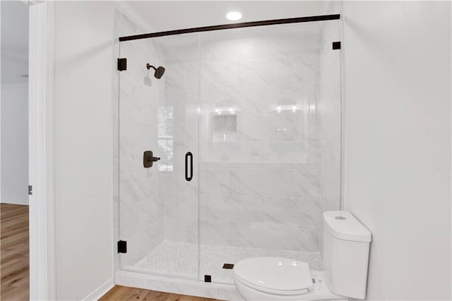 bathroom with crown molding, wood-type flooring, an enclosed shower, and toilet