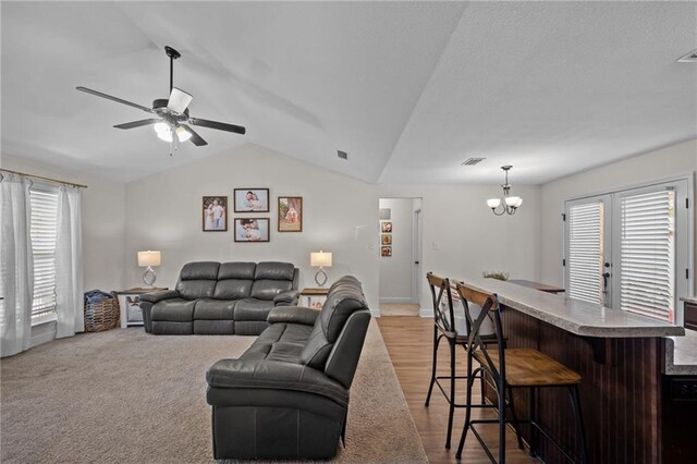9412 Fox Hunter Ct, Semmes, AL 36575 - living room with lofted ceiling, visible vents, a dry bar, and ceiling fan with notable chandelier