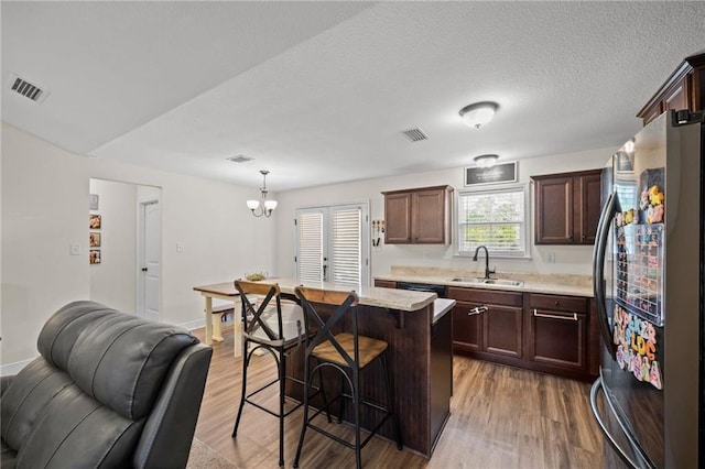 9412 Fox Hunter Ct, Semmes, AL 36575 - kitchen featuring a breakfast bar, wood finished floors, visible vents, a sink, and freestanding refrigerator
