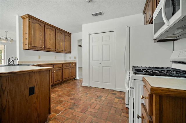 kitchen with hanging light fixtures, a notable chandelier, a textured ceiling, white gas range, and sink