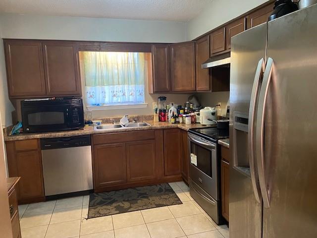 kitchen featuring light tile patterned flooring, appliances with stainless steel finishes, a textured ceiling, and sink