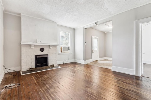 unfurnished living room with hardwood / wood-style floors, cooling unit, a brick fireplace, and a textured ceiling