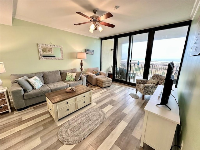 living area featuring a wall of windows, a ceiling fan, and light wood-style floors