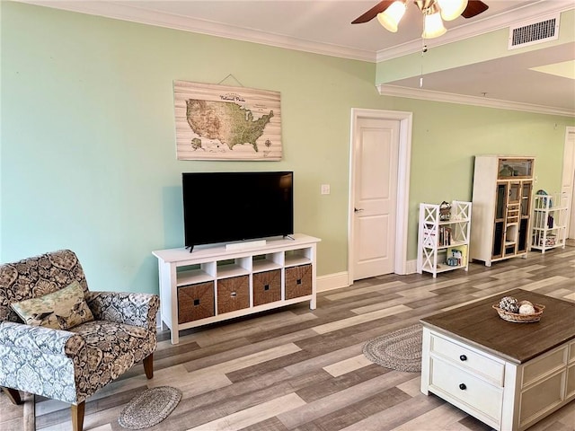 living area featuring visible vents, ornamental molding, a ceiling fan, wood finished floors, and baseboards