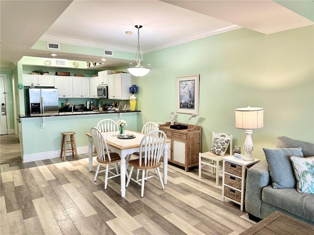 dining space featuring crown molding and light hardwood / wood-style floors