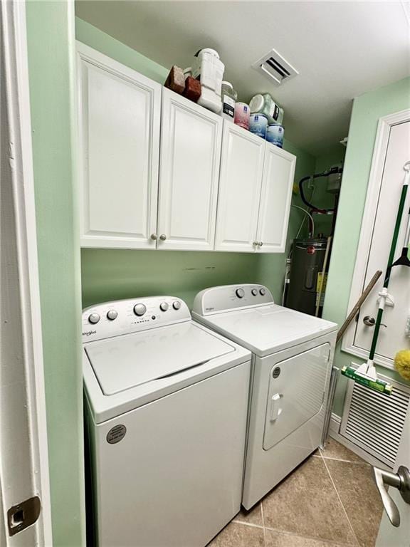 clothes washing area featuring light tile patterned flooring, cabinets, independent washer and dryer, and water heater