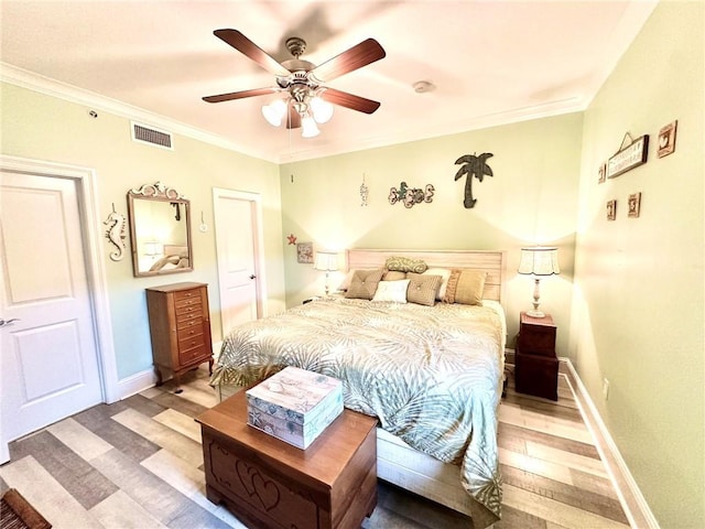 bedroom with light wood finished floors, baseboards, visible vents, and crown molding