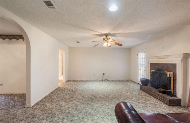 unfurnished living room with carpet flooring, ceiling fan, a textured ceiling, and a brick fireplace