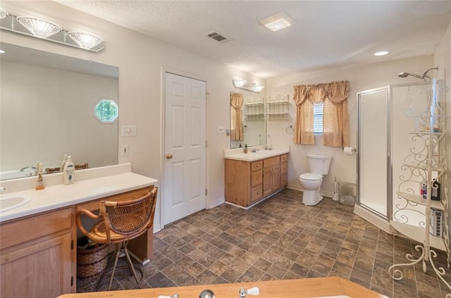 bathroom featuring vanity, a shower with shower door, a textured ceiling, and toilet