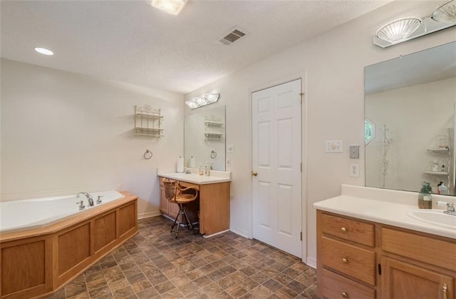 bathroom featuring a bathing tub, vanity, and a textured ceiling