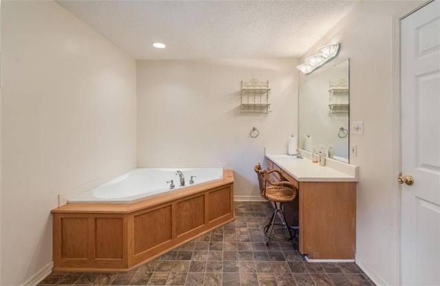 bathroom with vanity, a textured ceiling, and a tub to relax in