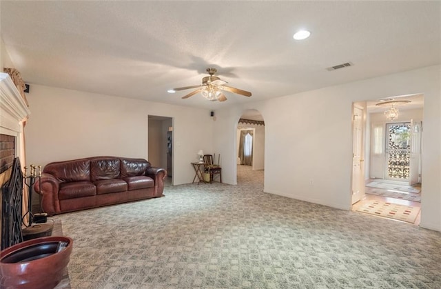 carpeted living room with ceiling fan and a brick fireplace