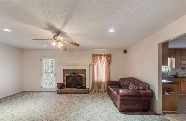 carpeted living room featuring a fireplace, a textured ceiling, and ceiling fan