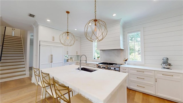 140E Mcgregor Ave S, Mobile, AL 36608 - kitchen featuring paneled refrigerator, a sink, premium range hood, a kitchen island with sink, and light countertops