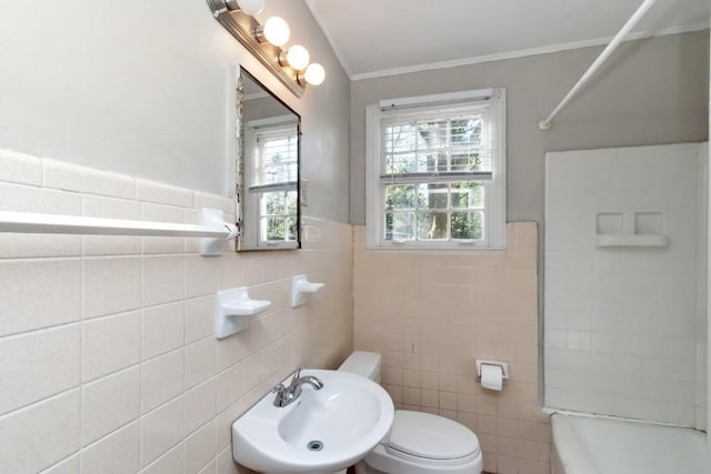 bathroom featuring a wainscoted wall, toilet, washtub / shower combination, ornamental molding, and a sink