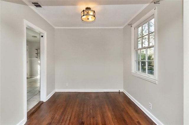 unfurnished room with baseboards, crown molding, visible vents, and wood finished floors