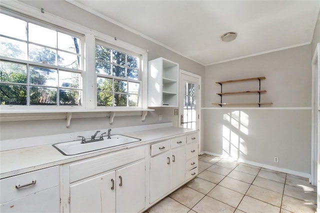 kitchen featuring open shelves, light countertops, ornamental molding, white cabinets, and a sink