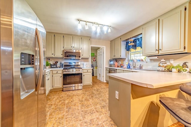 4698 Clarendon Dr, Mobile, AL 36619 - kitchen with stainless steel appliances, a peninsula, a sink, a kitchen breakfast bar, and light countertops