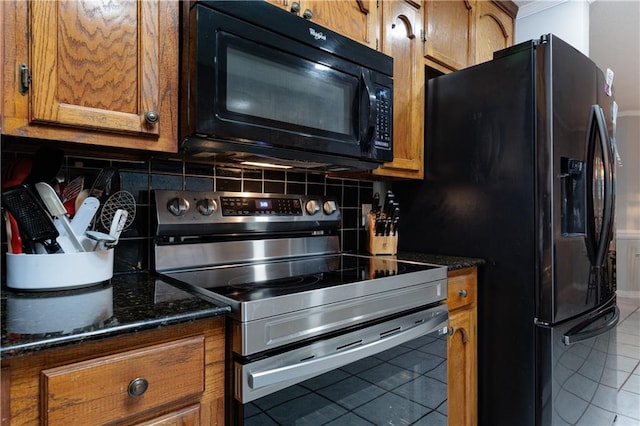 kitchen with dark stone countertops, black appliances, tasteful backsplash, and tile patterned flooring